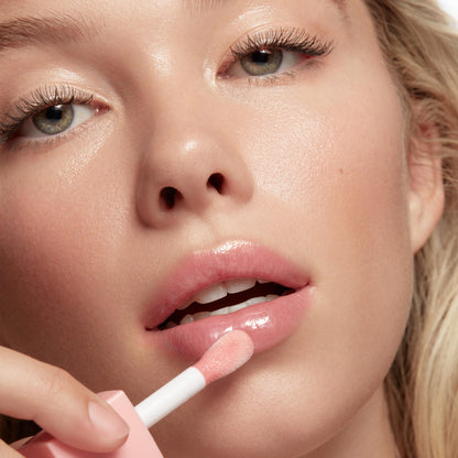 Sheer pink lip oil applicator glides onto glossy lips, delivering a hydrating, high-shine finish in a close-up beauty shot. ColourPop So Juicy Lip Oil Set, 100% Juicy, showcases the doe-foot wand and smooth, cushiony texture.