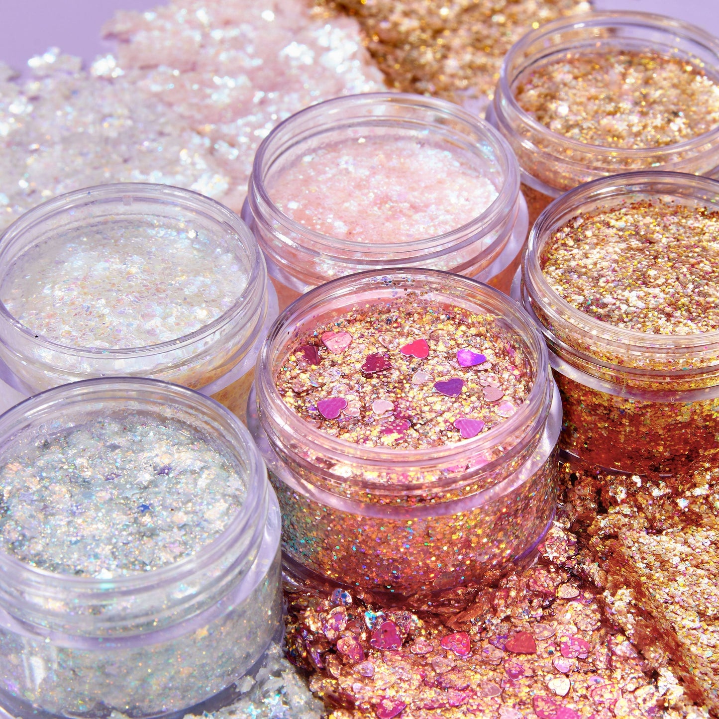 Disco Lady ColourPop Glitter Gel gleaming in open clear jars, swatched around them; iridescent silver, pink, and gold glitter with chunky flakes and heart confetti for face and body looks, styled on a pastel backdrop.